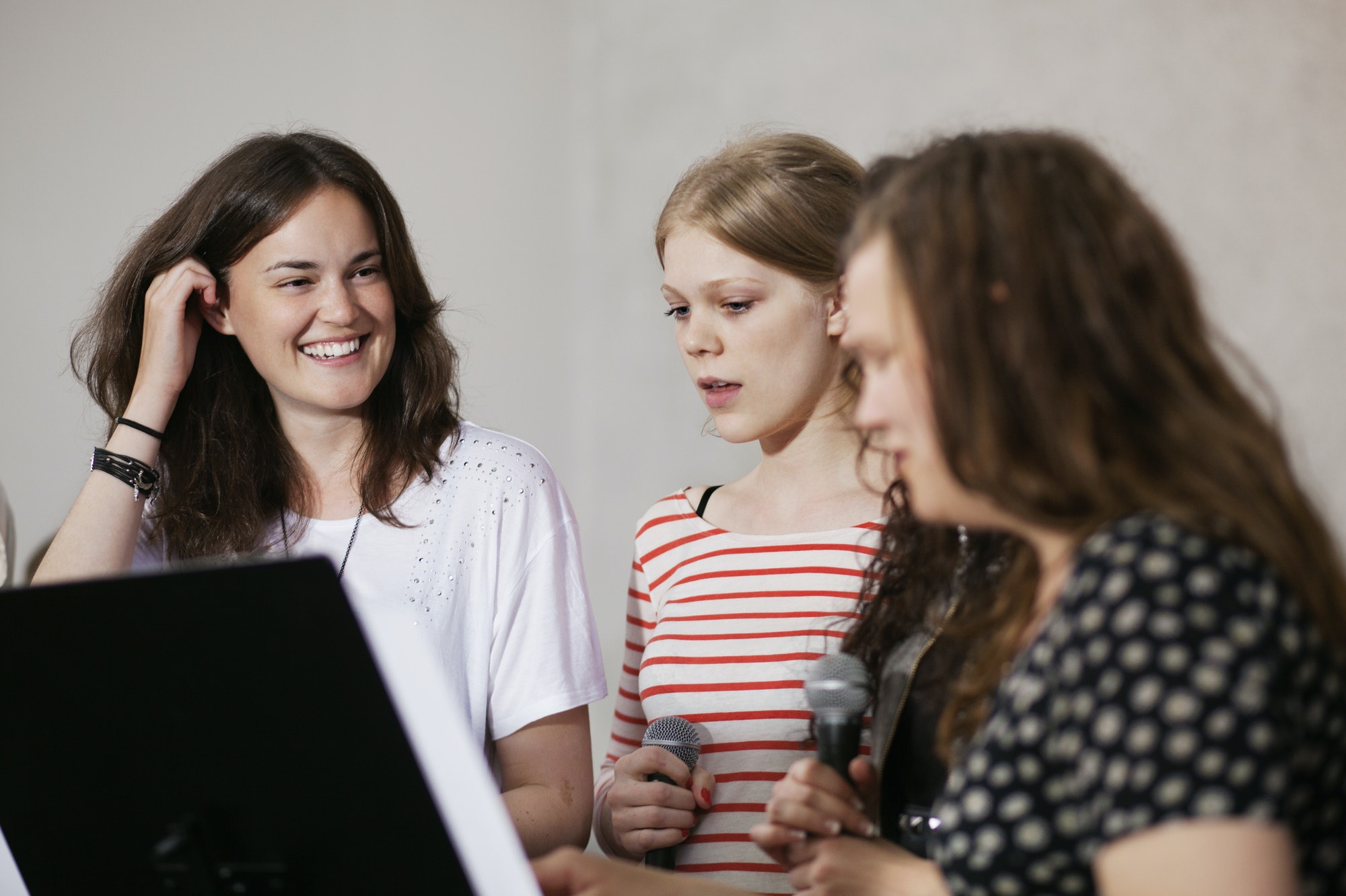 Happy female choir singers standing with microphones at church